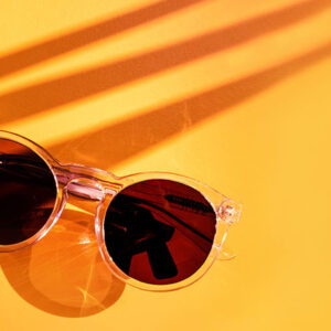 Palm leaf shadow with summer sunglasses on yellow background in