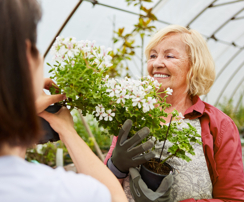 Friendly Suburban Garden Store Worker helping a customer with a plant