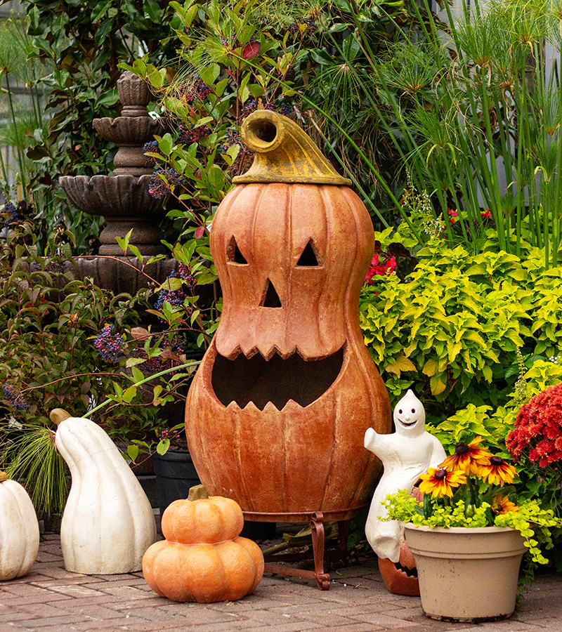 Halloween garden display with a jack o lantern ghost pumpkins fall flowers and seasonal décor