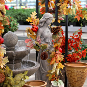 Fall garden display with a fountain statue autumn garland pumpkins pottery and seasonal floral décor